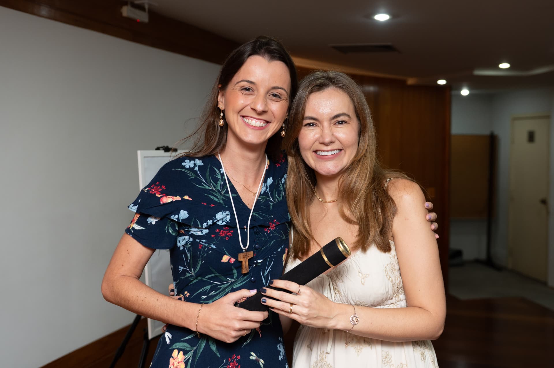 Turma 01 da Pós 2026 — aluna de vestido floral abraçada à formanda