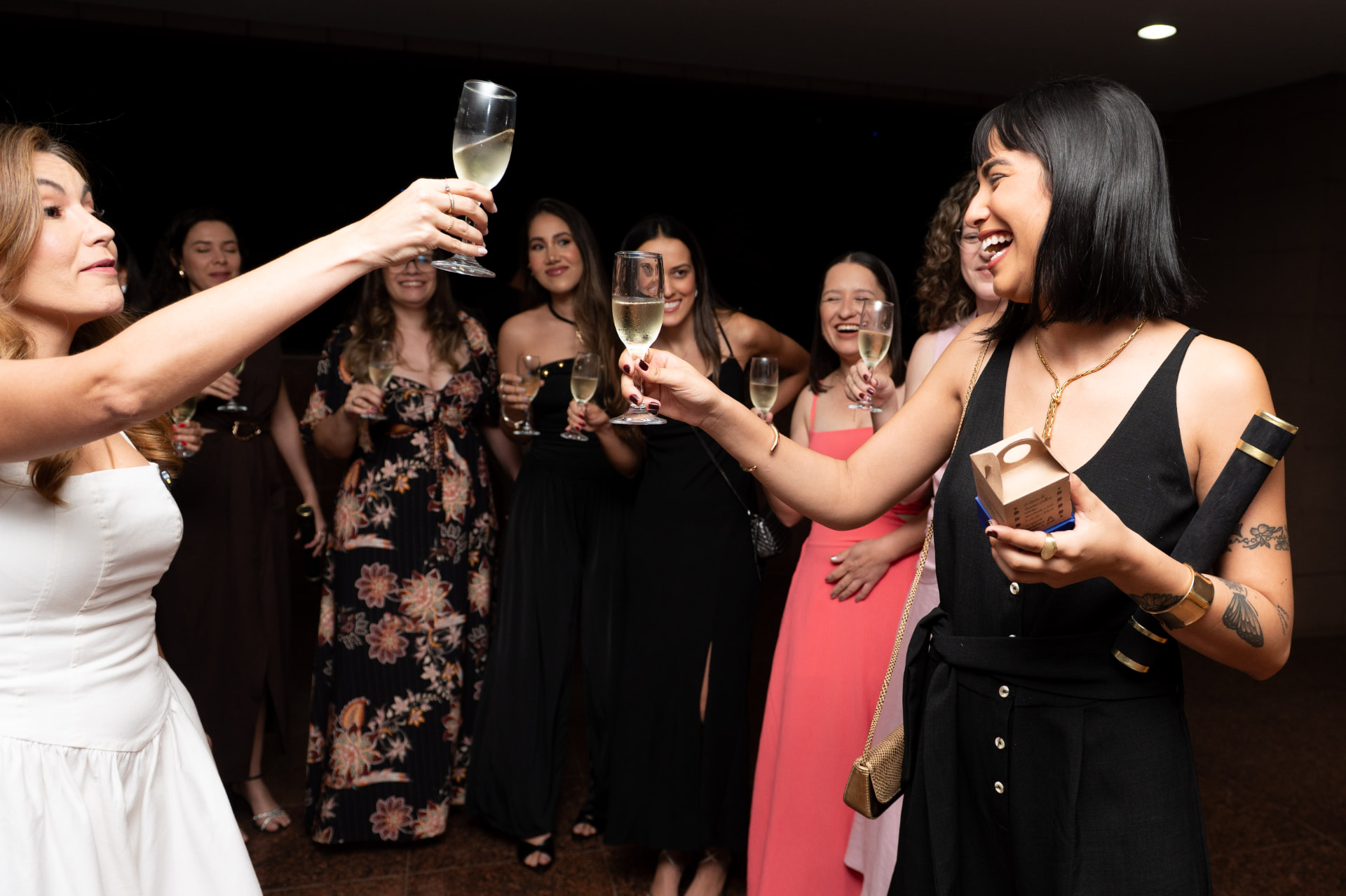 2ª turma — formandas celebrando, duas delas brindando com taças de champanhe